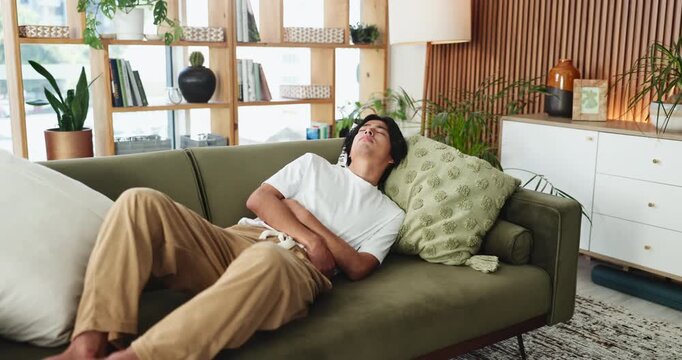 Man, stomach ache and sofa with pain for constipation, diarrhea or gastrointestinal reflux in home. Asian, male person or sore belly with cramp for food poisoning, indigestion or sickness in house