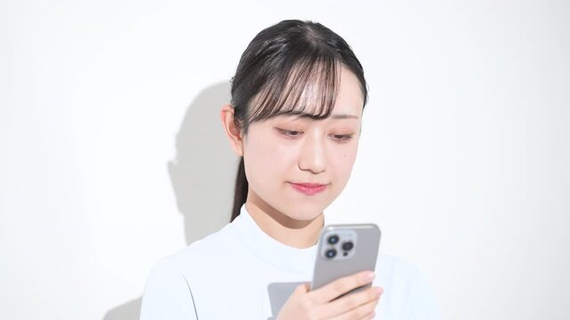 スマホを持つ女性看護師カメラ目線　転職や採用などのイメージ　スマホを見る、就活先や転職先を探す、検索する動画クローズアップ