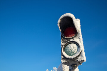 Frosty unused traffic light against clear blue sky