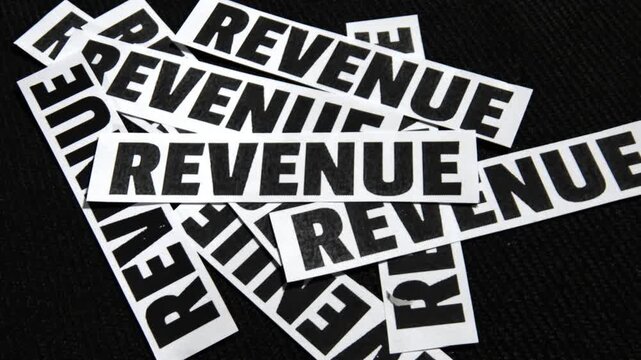 Revenue typography on scattered paper pieces against a black background representing business and finance concepts for creative projects
