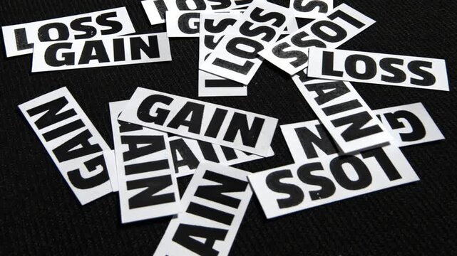 Typography on scattered paper pieces illustrating loss and gain concepts against a black backdrop for business and finance videos
