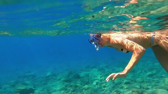 Woman in sea on face snorkelling mask swims underwater.  Trip into water all underwater world to see fish in vacation. Blue, clear water.