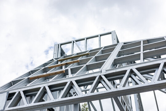 Close-up of a modern galvanized light steel frame LSF construction. Architectural details of roof trusses and wall framing against a blue sky. A sustainable and efficient building material.