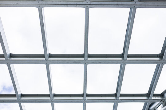 Close-up of a modern galvanized light steel frame LSF construction. Architectural details of roof trusses and wall framing against a blue sky. A sustainable and efficient building material.