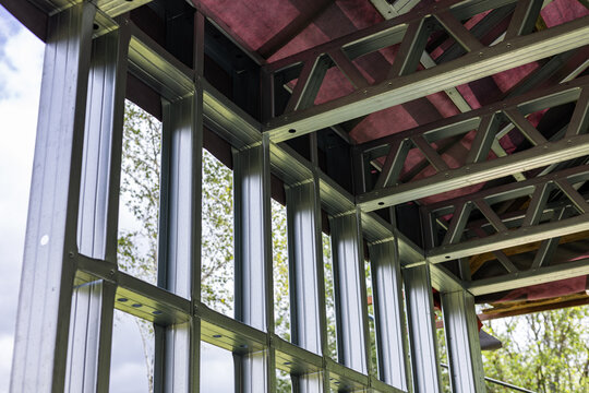 Close-up of a modern galvanized light steel frame LSF construction. Architectural details of roof trusses and wall framing against a blue sky. A sustainable and efficient building material.