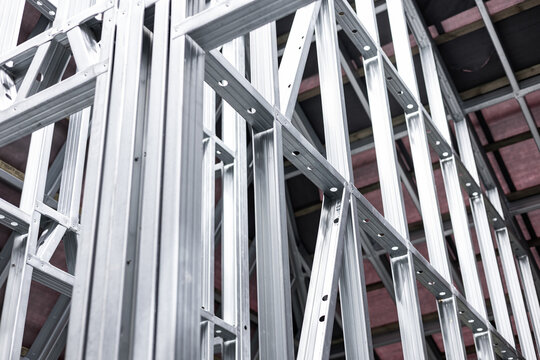 Close-up of a modern galvanized light steel frame LSF construction. Architectural details of roof trusses and wall framing against a blue sky. A sustainable and efficient building material.