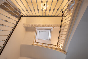 Perspectiva en contrapicado del hueco de una escalera con dise&ntilde;o geom&eacute;trico y l&iacute;neas arquitect&oacute;nicas