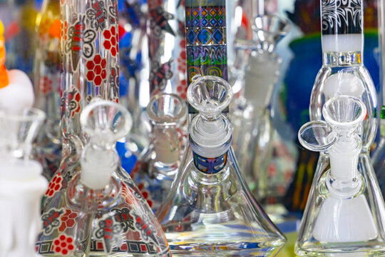 Glass bongs for smoking displayed on store shelves, colorful water pipes and smoking accessories in a modern retail shop.