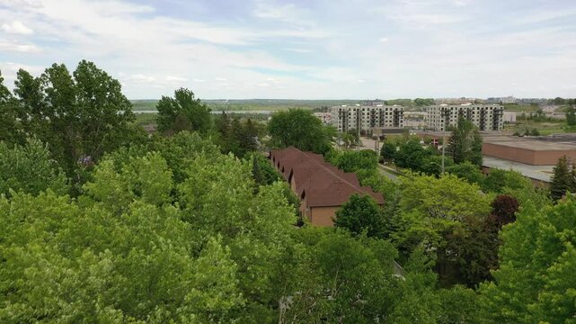 Aerial view over lush spring forest canopy with suburban homes and lake simcoe on the horizon near barrie, ontario. Barrie ontario