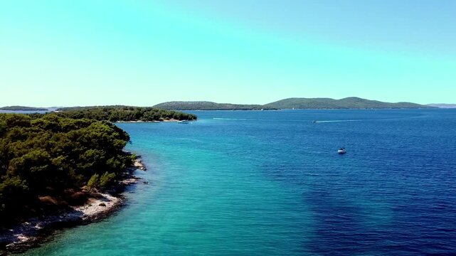 Aerial pan of forested coastline meeting clear blue Adriatic Sea, Seget Vranjica Croatia