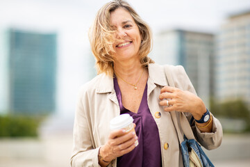 Stylish senior woman holding coffee cup in urban environment