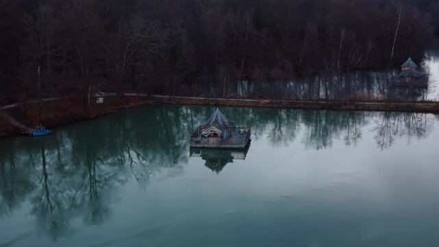 Aerial: close up of wooden house on Verchat pond and Cabanes des Grands Reflets during the day in Joncherey, France, orbit drone shot
