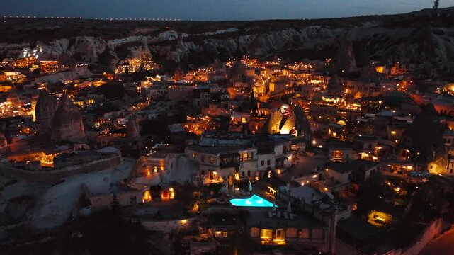 Night panorama of Cappadocia with illuminated fairy chimneys and town lights, Turkey