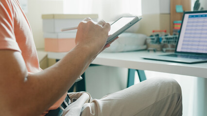 Closeup young Asia male entrepreneur small business confirm purchase order from customer parcel barcode tracking number on digital tablet check inventory product ready shipping at online retail shop.