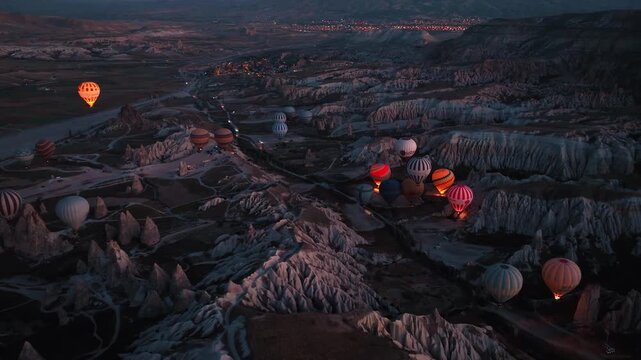 Hot air balloons floating above the iconic fairy chimneys and rock formations of Cappadocia, Turkey, during sunrise.