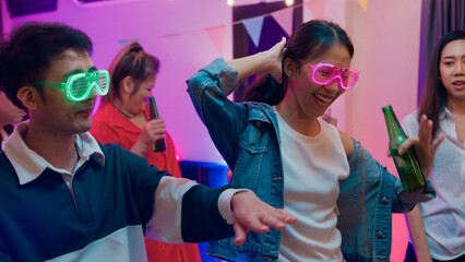 Diverse group multiethnic young adult Asia friend wear futuristic neon glowing glasses dance and drink alcohol beer fun hangout party in living room night indoor home. Disco lights illuminating house.