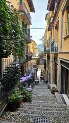 Fototapeta premium Narrow European street with stone stairs, colorful balconies, and flowers. Traditional architecture and romantic travel destination.