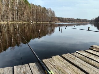 Spring fishing on the lake from a wooden bridge, fishing with a rod.