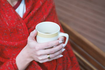 Young girl wrapped in plaid with cup of tea in hands