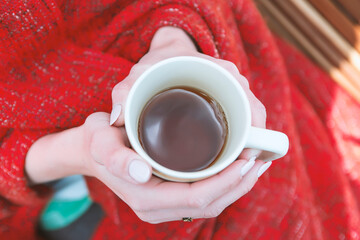 Young girl wrapped in plaid with cup of tea in hands