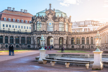Naklejka premium Visitors walk around the Zwinger Palace in Dresden, Germany. The majestic buildings stand tall under the winter sun as people enjoy the festive atmosphere during Christmas time.