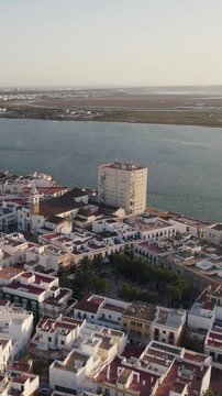 Vertical aerial orbiting shot above Ayamonte, showcasing traditional white seaside buildings along the southern Spanish coast.