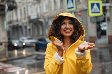 Fototapeta premium Against the building at background. Happy young woman in the city during the rain