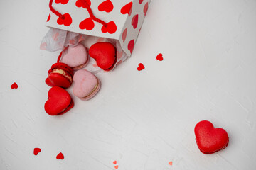 Heart shaped red and pink macarons spilling out of a white gift bag with red hearts, celebrating love and sweet moments on a white background with scattered confetti, perfect for Valentine's Day