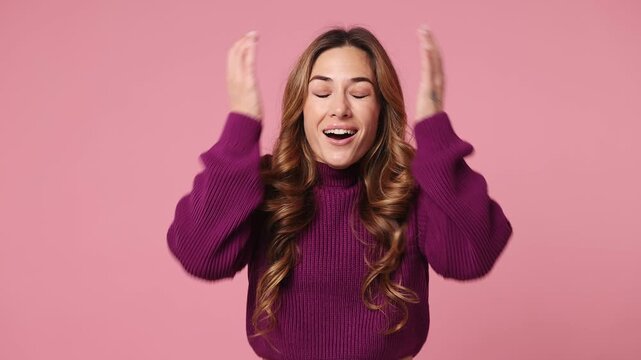Young woman wear purple knitted sweater casual clothes look camera surprised ask what wow omg no way doing winner gesture say yes celebrating put hands on face isolated on plain pastel pink background