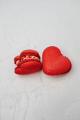 Red heart-shaped macarons resting on a white textured surface, symbolizing love, romance, and sweet confectionery, perfect for Valentine's Day celebrations and gifting