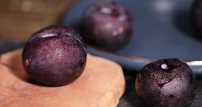 sliced fresh juicy plums on the kitchen table, some beautiful pure black plums on the table, plum with red juicy sweet flesh cut into pieces