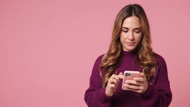 Young woman she wear purple knitted sweater casual clothes hold in hand use mobile cell phone indicate index finger aside on workspace area copy space mock up isolated on plain pastel pink background