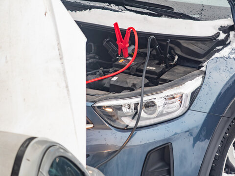 Car is being jump started in snowy weather in winter season during daylight hours