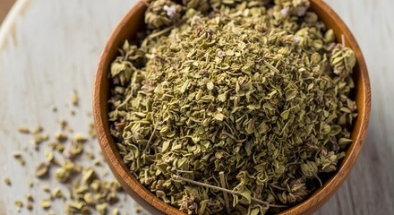 Close up of dried oregano in a wooden bowl on a white surface