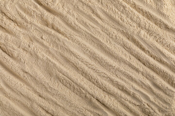 A top-down macro photo shows a uniform layer of high-quality beige herbal powder, with a series of horizontal ridges and a smooth, matte texture.