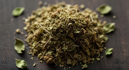 Close up of dried oregano pile with scattered leaves on a dark surface