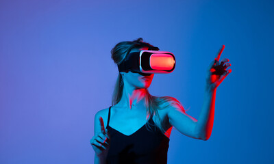 Woman experiencing virtual reality with hand gestures under neon blue and red lighting, immersive...