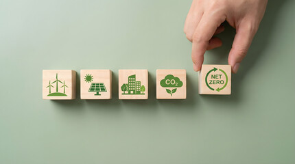 Human hand places net zero block among symbols for clean energy and green environment