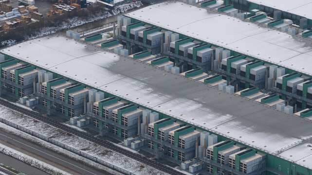 Aerial view of the Agriport datacenters covered in a blanket of snow, the cold white contrasting with the green and grey structures, Middenmeer, North Holland, Netherlands.