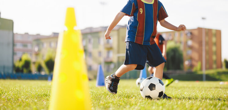 Youth Soccer Training Drill With Cone. Child Practicing Dribbling and Ball Control Outdoors