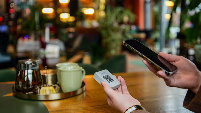 Customer scanning QR code on table for contactless payment or menu access in a restaurant
