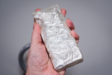 Silver bullion bar in hand. Silver price record. Physical precious metal investment.