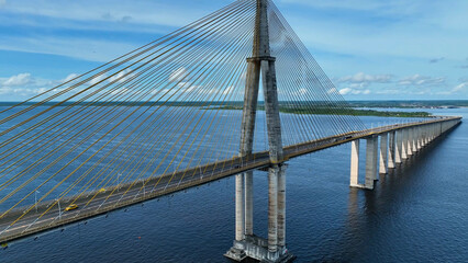 Fototapeta premium Suspension Cable Bridge In Manaus Amazonas Brazil. Birds Eye View Of Suspension Bridge With Cars Driving Across. Shore Clouds Sky Beach Sea. Shore Beach Scenic Coastline. Manaus Amazonas.