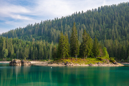 View of Cauma Lake Caumasee with crystal blue turquoise water and rocky beach in beautiful mountain landscape with pine forest, Flims, Graubuenden, Switzerland.