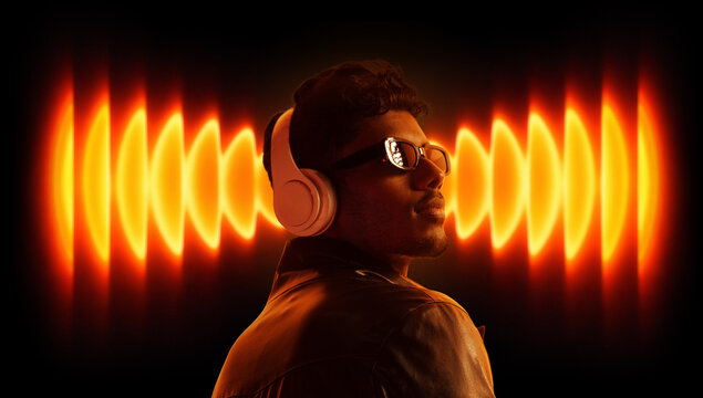 Dynamic design portrait of man with headphones and orange sound waves. Concept of powerful music, sound intensity, audio branding, emotional response and modern media experience.