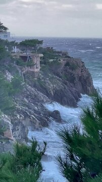 Vertical video. Huge storm waves in the Mediterranean Sea crash against a rocky shore. 0.9x slow motion. Mallorca, Spain.