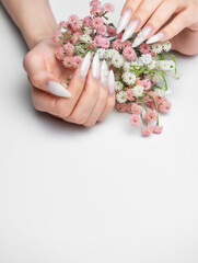 Woman's hands with white ombre stiletto nails holding flowers © Olena Rudo