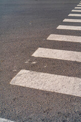 Close-up of pedestrian crosswalk markings on asphalt road surface. Urban traffic concept with road safety, transportation, and city infrastructure background.