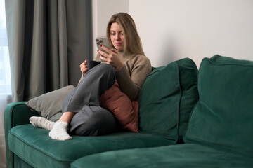 Obraz premium Quiet Afternoon Browsing Her Phone on a Green Sofa
