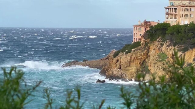 Storm waves in the Mediterranean Sea crash against the rocks of a rocky shore. 0.8x slow motion video. Mallorca, Spain.